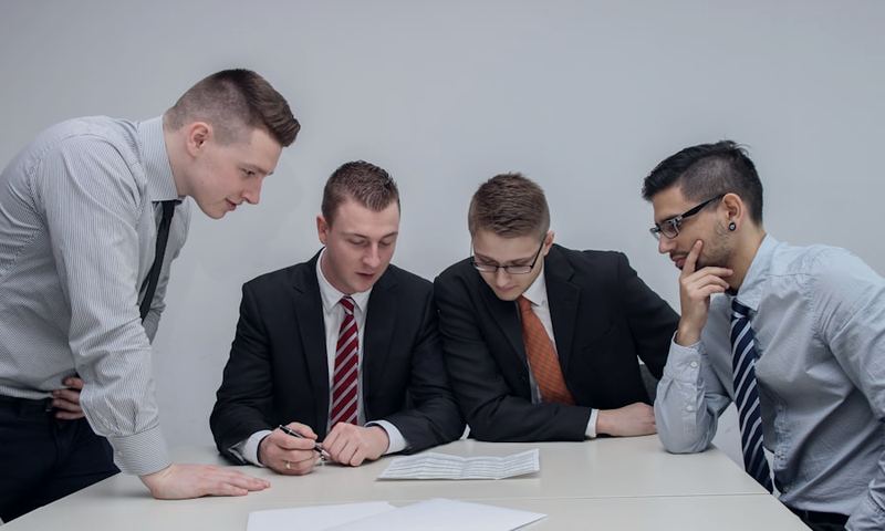 Four colleagues reviewing a printed document together at a table