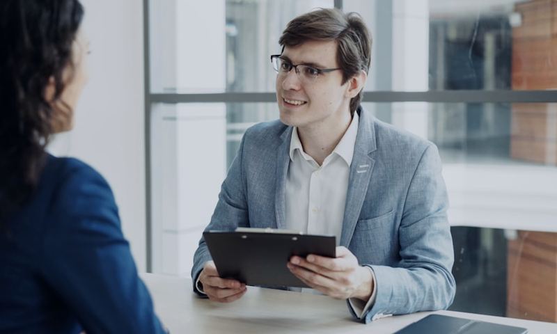 An interviewer taking structured notes on a clipboard